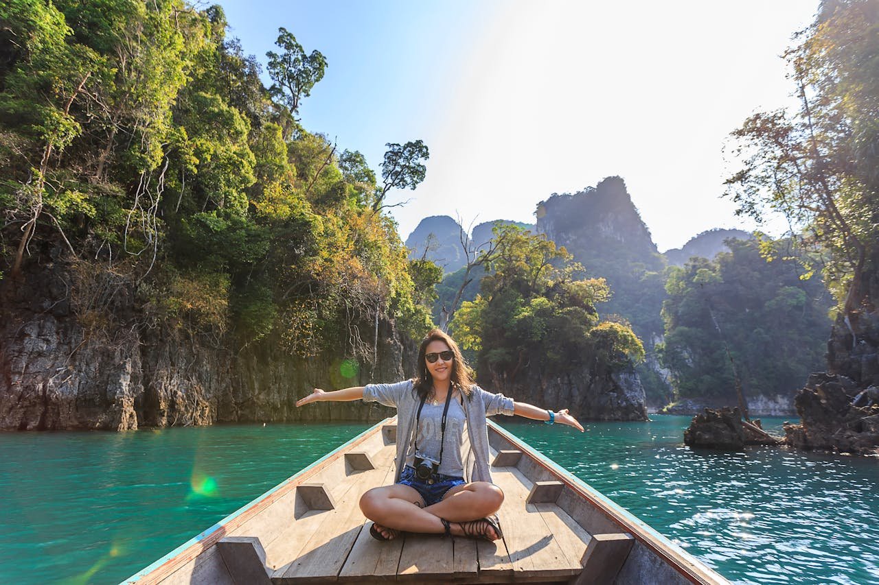 Services-01 Asian woman relishing a serene boat journey through the lush karst landscape of Thailand's Khlong Sok.