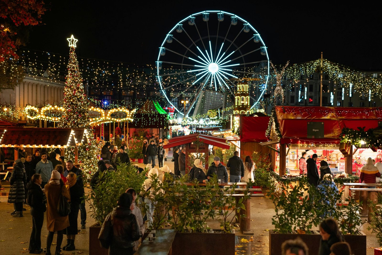 Festive night scene at Poznań's Christmas market featuring a ferris wheel and illuminated stalls.