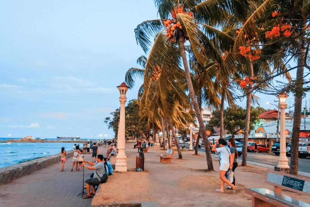 People stroll along a vibrant seaside promenade with palm trees and ocean in Mexico