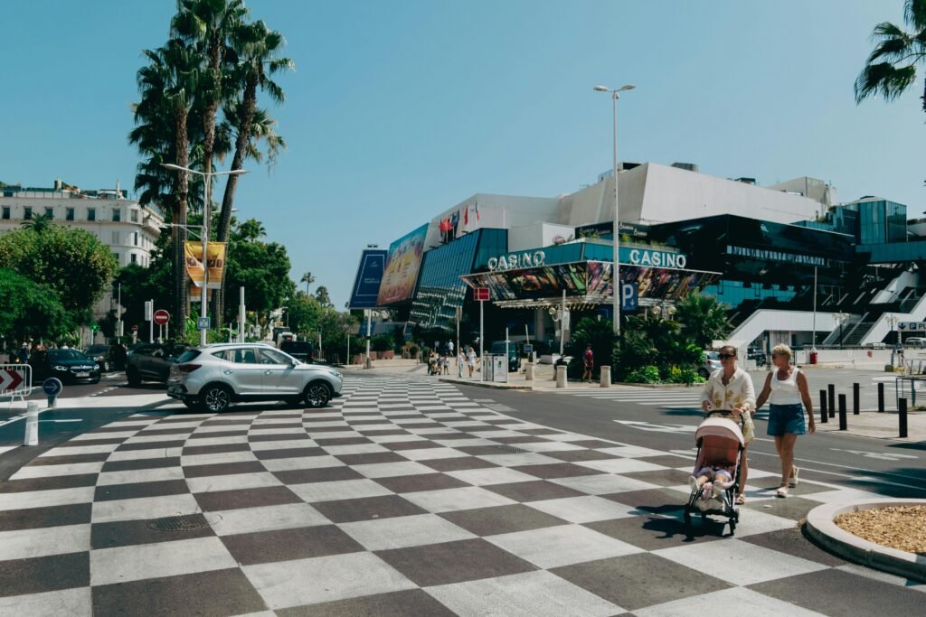 Daytime view of Cannes promenade featuring casino, people walking, and palm trees.