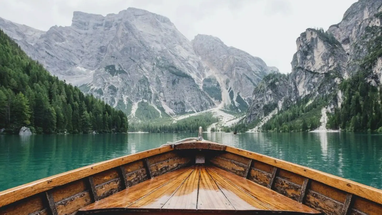 Scenic alpine lake viewed from a wooden boat, surrounded by mountains